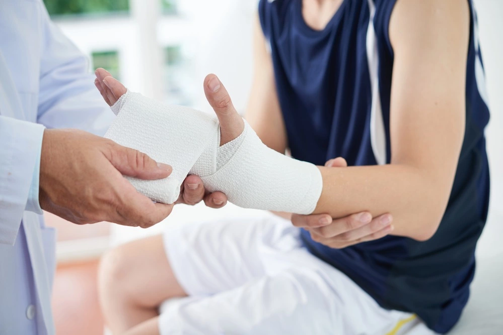 A doctor is bandaging a boy's wrist
