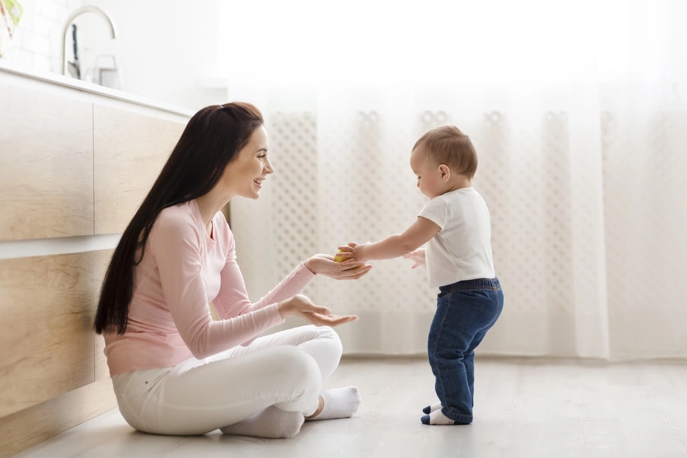 A mom is sitting on the floor of a bathroom with her toddler
