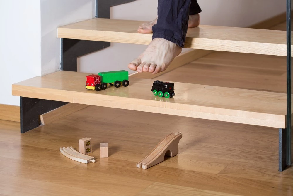 A person walking down wood steps with toys on the steps.