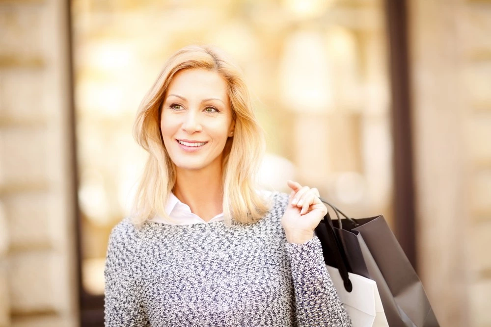 A woman dressed for fall weather with a shopping bag.