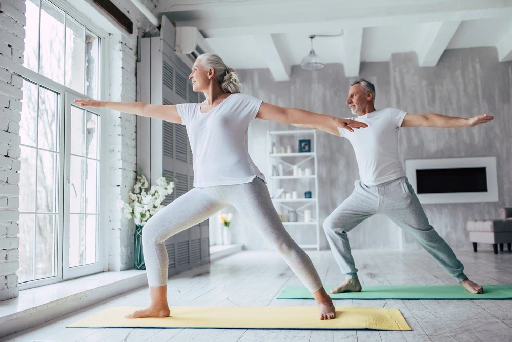 a healthy senior couple doing yoga in their home