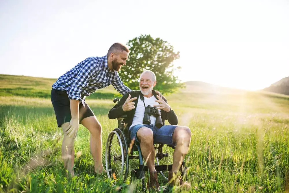 A man with his father in a wheelchair in a field