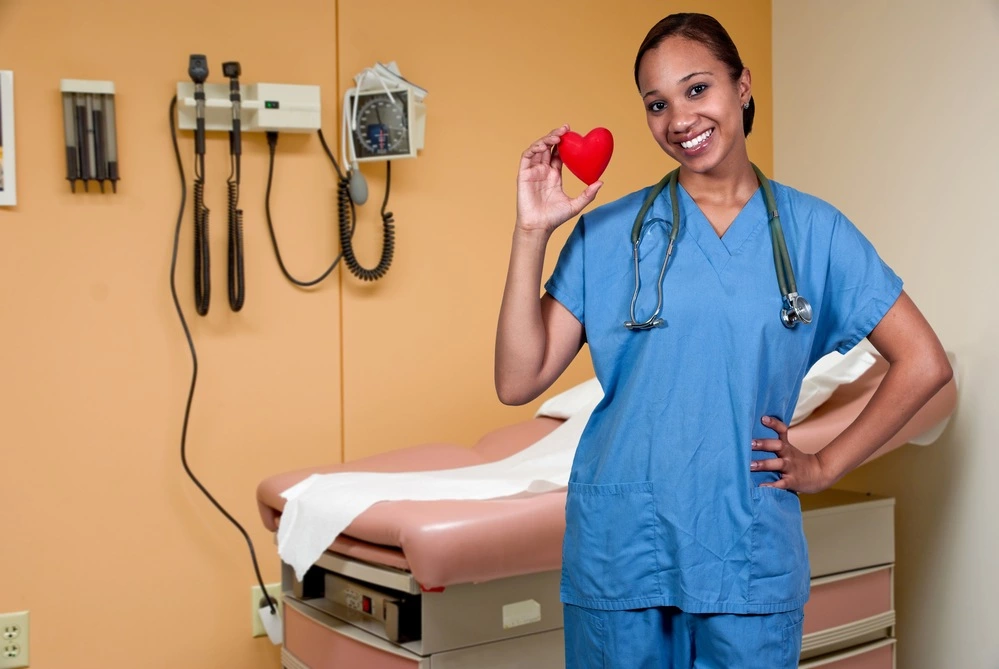 A doctor or medical student in an empty patient room smiling