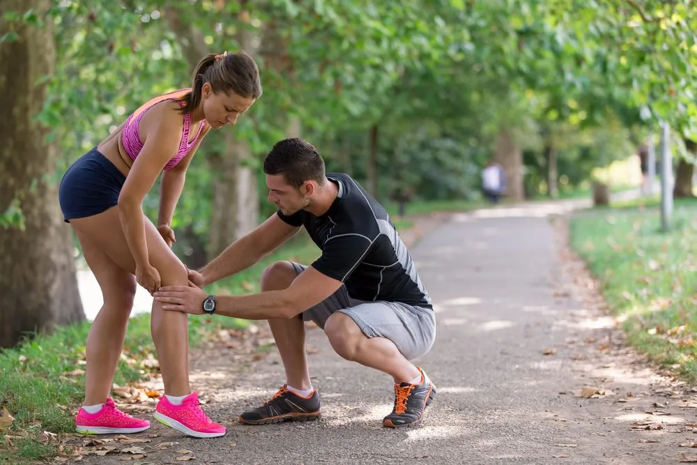 A man is looking a the knee of a woman while the couple is on a run.