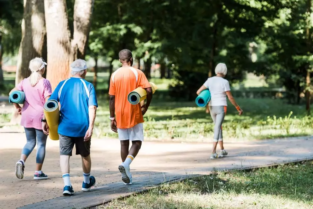 People walking with yoga mats in athletic attire.